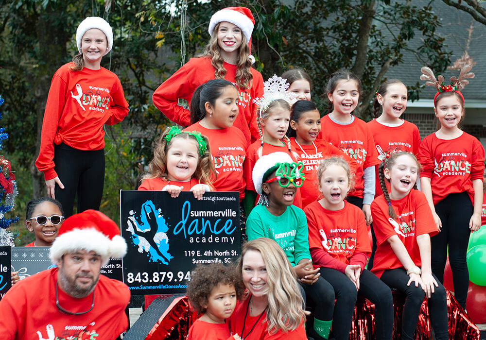 Summerville Dance Academy students in Santa hats ride their parade float