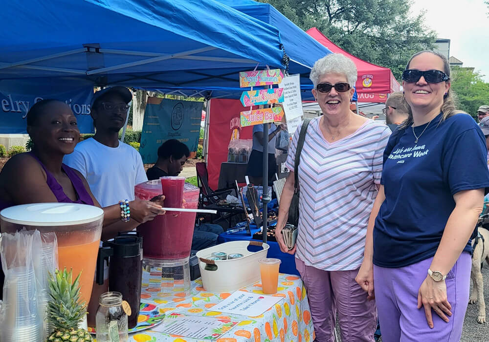 A vendor pours fresh juice for shoppers at her booth