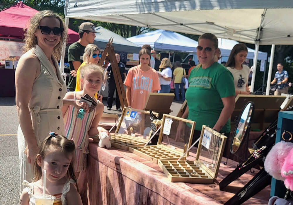 A family browses handmade jewelry at an artisan booth